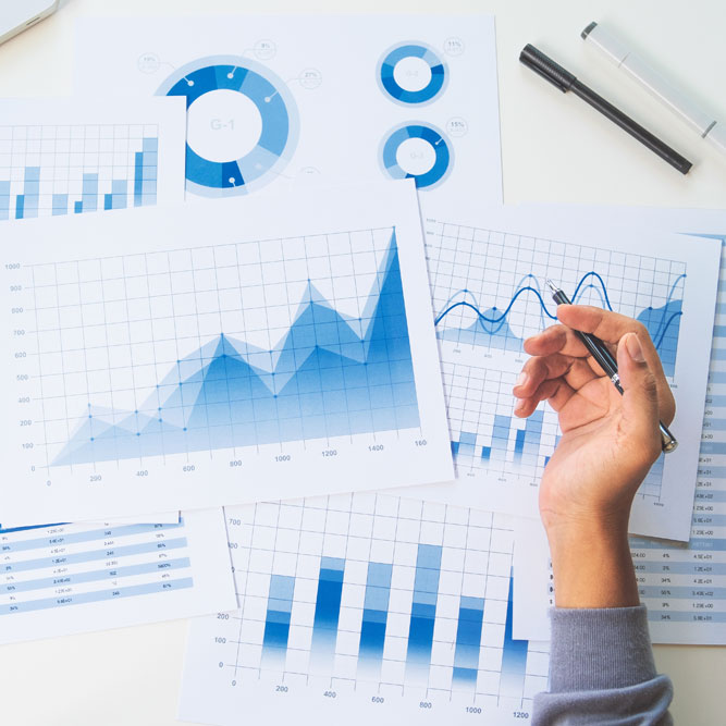 kamay na may hawak na panulat sa ibabaw ng mga ulat